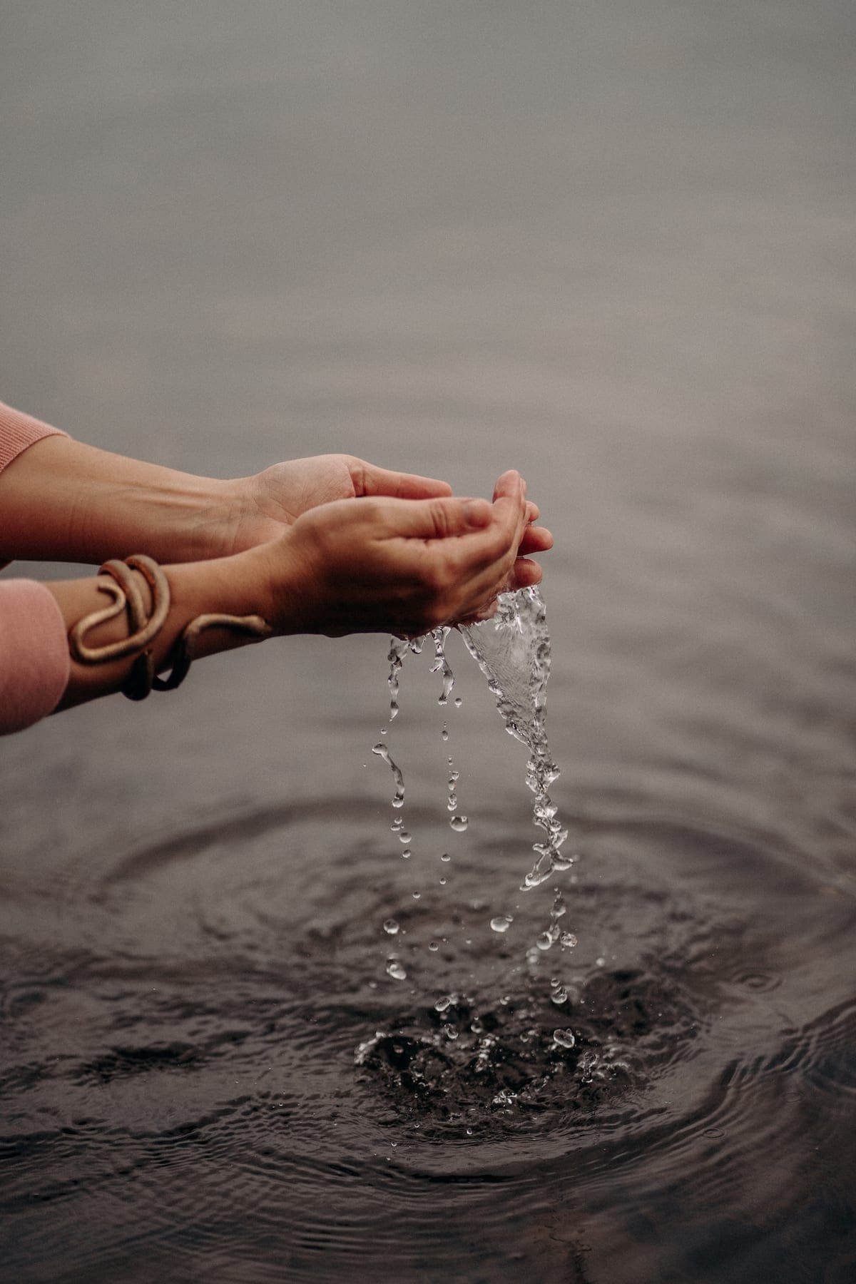 Cupped hands lifting water, ripples spreading
